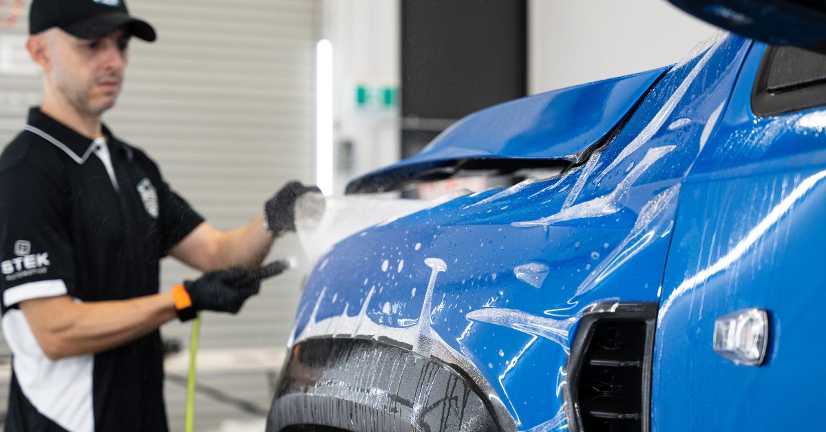 Radikal Wraps applying paint protection film on a blue Ram TRX, showcasing expertise in PPF maintenance and tailored paint protection